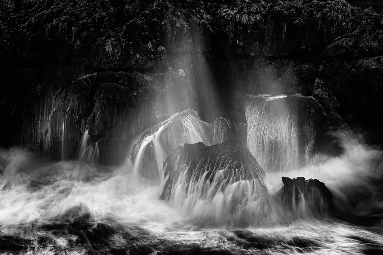 Paysage côtier des Asturies en Espagne. Les vagues de l'océan Atlantique se brisent sur des rochers. Photographie d'art en noir et blanc par Amar Guillen, artiste photographe.